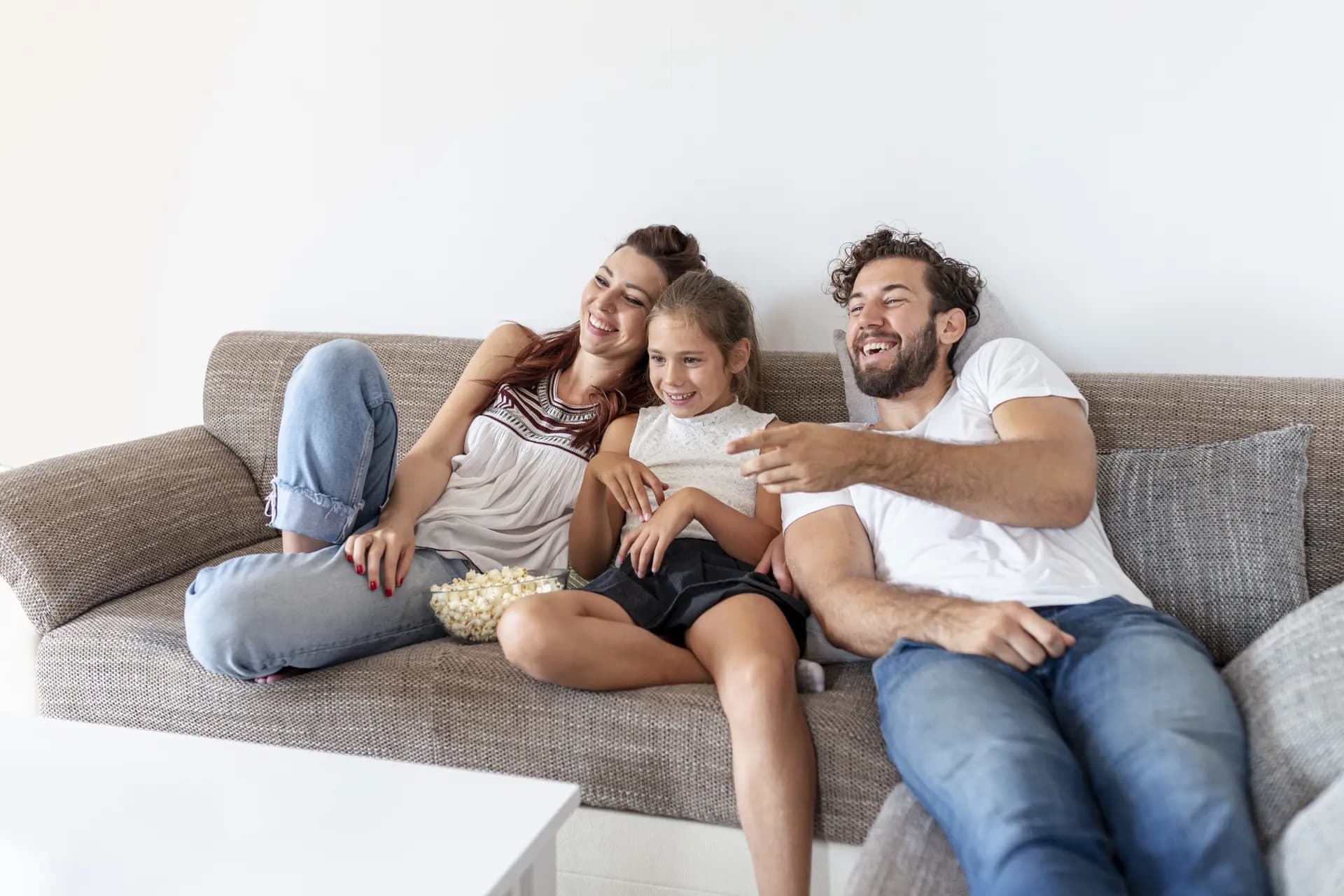 Familia sonriendo frente a la pantalla en la sala