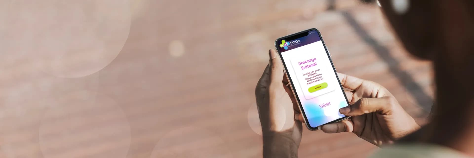 Manos sosteniendo un celular con la confirmación de una recarga Netmas